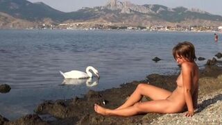 A naked girl is having fun on the riverbank, capturing a daring moment