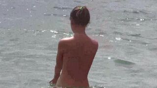 A bunch of naked people on the beach enjoying their bodies