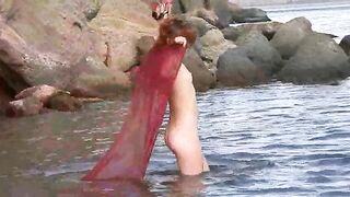 A sexy girl is walking on the wet beach almost naked