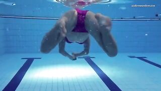 A beautiful naked girl is swimming in the pool under water