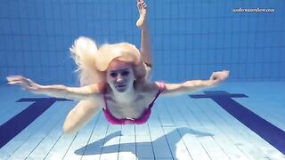 A beautiful naked girl is swimming in the pool under water