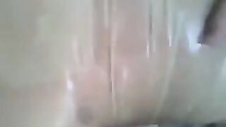 A guy masturbates his dick with his hand covered with condom