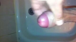 The kid stands in the shower and jerks off his dick with his hand until the end