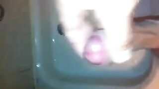 The kid stands in the shower and jerks off his dick with his hand until the end