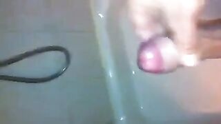 The kid stands in the shower and jerks off his dick with his hand until the end